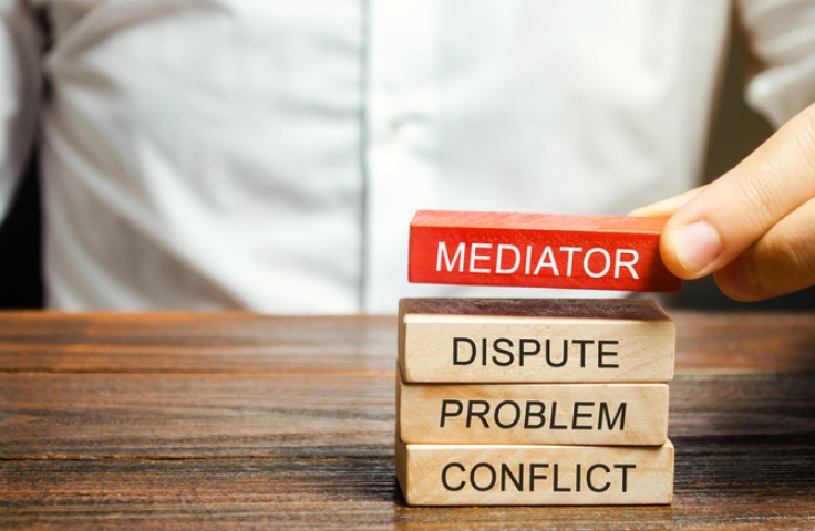 man holds wooden blocks with the word Mediator