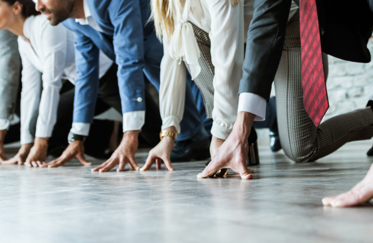 People in business attire preparing for a sprint 