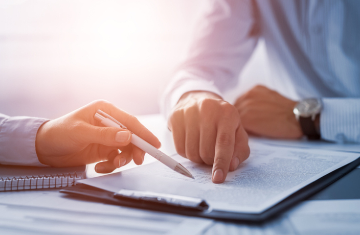 two people signing a contractual document 